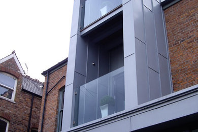 Gey industrial house exterior in Sussex with three floors, mixed cladding and a flat roof.