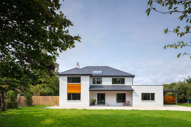 Idées déco pour une grande façade de maison grise moderne en stuc à un étage avec un toit à deux pans et un toit en tuile.