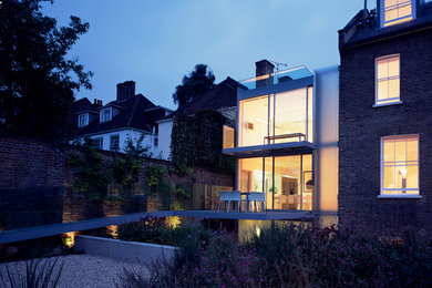 ロンドンにある高級な中くらいなコンテンポラリースタイルのおしゃれな三階建ての家 (ガラスサイディング) の写真