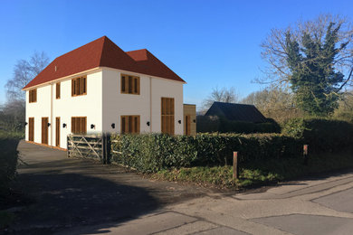 This is an example of a large contemporary two floor render detached house in Kent with a pitched roof and a tiled roof.