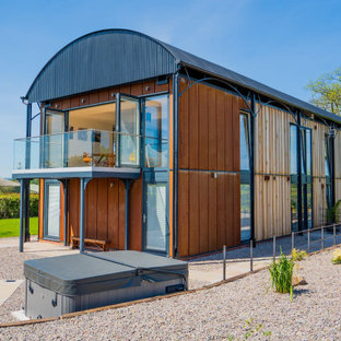 Exempel på ett stort modernt oranget hus, med två våningar, metallfasad och tak i metall