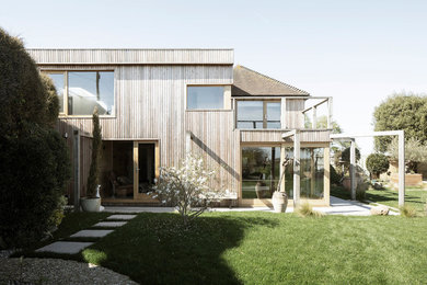 Diseño de fachada de casa marrón marinera grande de dos plantas con revestimiento de madera, tejado plano y techo verde