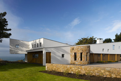 This is an example of a white contemporary split-level house exterior in Channel Islands with mixed cladding.