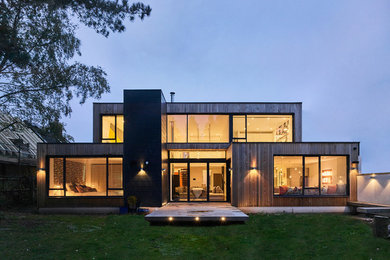 Diseño de fachada de casa actual de tamaño medio de dos plantas con revestimiento de madera y tejado plano