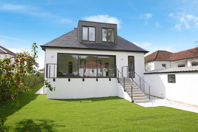 Modelo de fachada de casa blanca contemporánea grande de dos plantas con revestimiento de estuco, tejado a dos aguas y tejado de teja de barro