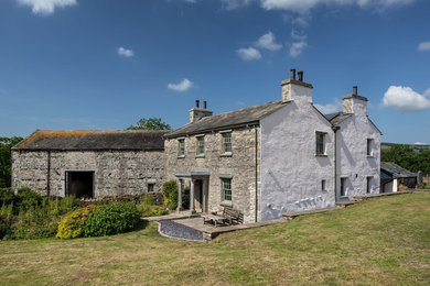 Imagen de fachada de casa gris tradicional grande de dos plantas con revestimiento de piedra, tejado a dos aguas y tejado de teja de barro