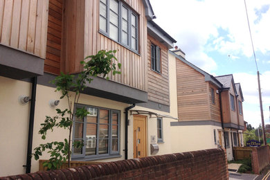 This is an example of a medium sized contemporary two floor house exterior in Hampshire with wood cladding.