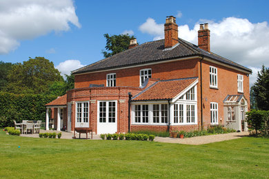 Photo of a red traditional two floor brick detached house in Other with a tiled roof.