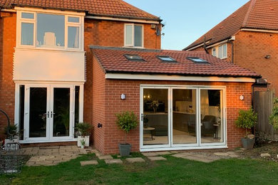 This is an example of a medium sized contemporary two floor brick semi-detached house in West Midlands with an orange house, a lean-to roof and a tiled roof.