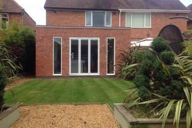 Medium sized and multi-coloured modern bungalow brick semi-detached house in West Midlands with a flat roof and a mixed material roof.