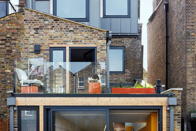 This is an example of a large contemporary rear extension in London with three floors and mixed cladding.