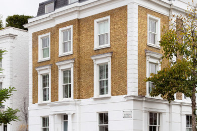 Large victorian brick terraced house in London with four floors, a mansard roof, a tiled roof and a black roof.