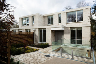 Photo of a large and beige contemporary brick semi-detached house in London with three floors, a flat roof and a mixed material roof.
