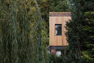Ejemplo de fachada de casa multicolor moderna de tamaño medio de dos plantas con revestimiento de madera, tejado plano y tejado de metal