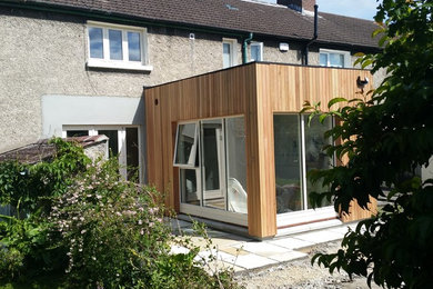 Photo of a gey scandinavian two floor house exterior in Dublin with wood cladding and a pitched roof.