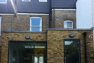 Design ideas for a medium sized and yellow contemporary brick house exterior in London with three floors and a flat roof.