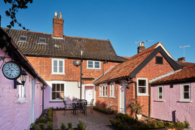 他の地域にある中くらいなトラディショナルスタイルのおしゃれな家の外観 (レンガサイディング、ピンクの外壁、タウンハウス) の写真
