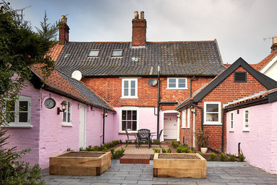 Imagen de fachada de casa pareada rosa tradicional de tamaño medio de dos plantas con revestimiento de ladrillo, tejado a dos aguas y tejado de teja de barro