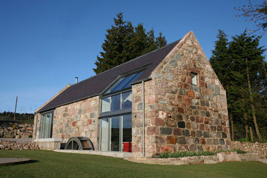 This is an example of a medium sized contemporary two floor house exterior in Other with stone cladding and a pitched roof.