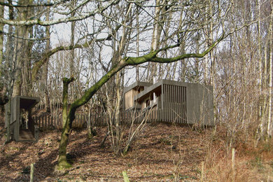 Réalisation d'une petite façade de maison marron champêtre en bois de plain-pied avec un toit plat.