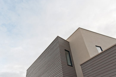 This is an example of a medium sized contemporary two floor house exterior in London with wood cladding and a flat roof.