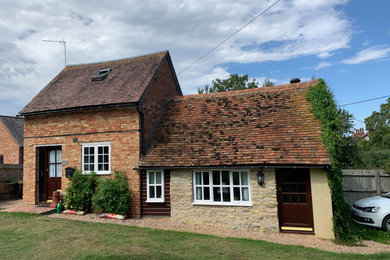 Photo of a medium sized and gey rustic two floor detached house in Oxfordshire with wood cladding, a pitched roof, a tiled roof and a red roof.