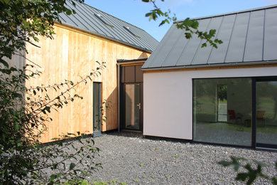 Cette photo montre une façade de maison blanche moderne en bois de taille moyenne et à un étage avec un toit à deux pans et un toit en métal.