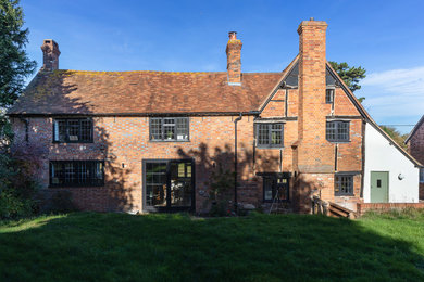 This is an example of a large and yellow farmhouse brick detached house in Oxfordshire with three floors, a pitched roof and a tiled roof.