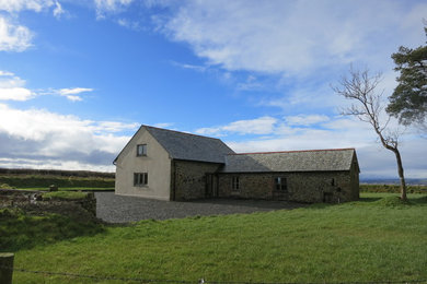 Ejemplo de fachada de casa gris de estilo de casa de campo de tamaño medio de dos plantas con revestimiento de piedra, tejado a dos aguas y tejado de teja de barro