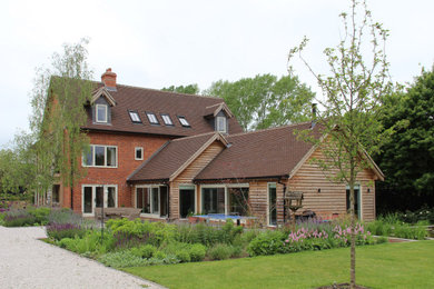 This is an example of a contemporary brick detached house in Other with three floors, a pitched roof and a tiled roof.