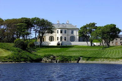 Immagine della facciata di una casa grande bianca classica a tre piani con rivestimento in stucco e tetto a capanna