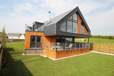 Réalisation d'une façade de maison multicolore design en bois de taille moyenne et à un étage avec un toit à deux pans et un toit en tuile.