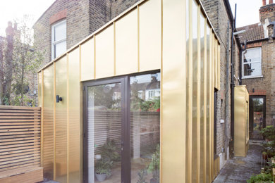 Gey contemporary bungalow terraced house in London with metal cladding and a lean-to roof.