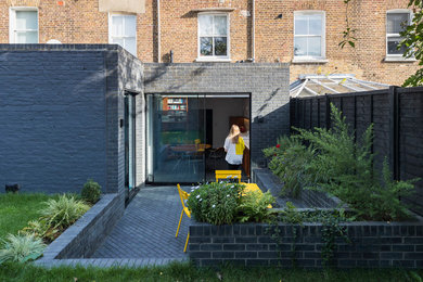 Diseño de fachada de casa pareada negra contemporánea de una planta con revestimiento de ladrillo, tejado plano y tejado de varios materiales