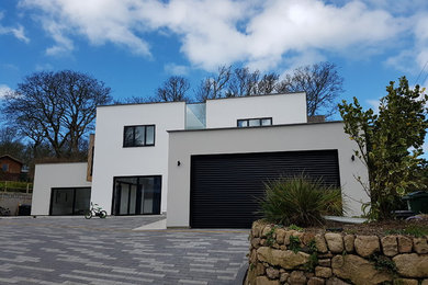 Photo of a large and white contemporary two floor house exterior in Cornwall with mixed cladding and a flat roof.