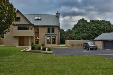 Large and beige contemporary house exterior in Other with three floors, stone cladding and a pitched roof.