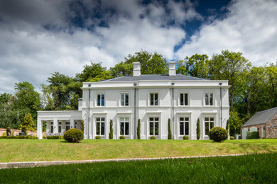 Immagine della villa grande classica a due piani con rivestimento in stucco, tetto a padiglione e copertura a scandole