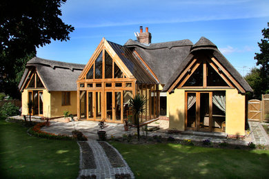 Photo of a yellow rustic render detached house in Hampshire with a pitched roof and a mixed material roof.