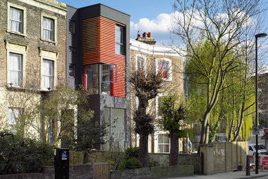Diseño de fachada de casa negra actual pequeña de tres plantas con revestimiento de metal, tejado plano y techo verde