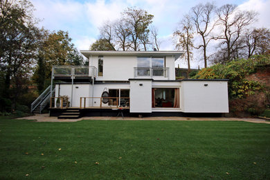 Diseño de fachada de casa blanca actual de tamaño medio de dos plantas con revestimiento de estuco y tejado plano