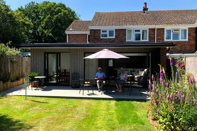 Photo of a medium sized contemporary bungalow semi-detached house in Hampshire with wood cladding and a flat roof.