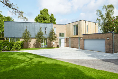 Medium sized and gey modern two floor house exterior in Oxfordshire with mixed cladding and a flat roof.