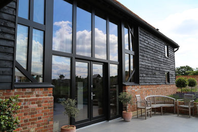 Large and black contemporary split-level house exterior in Buckinghamshire with wood cladding.