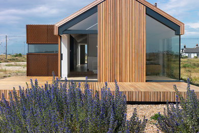 Diseño de fachada actual de una planta con revestimiento de madera y tejado a dos aguas