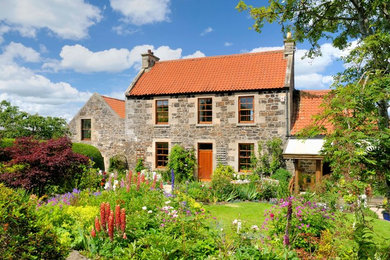 This is an example of a traditional two floor house exterior in Other with stone cladding and a pitched roof.
