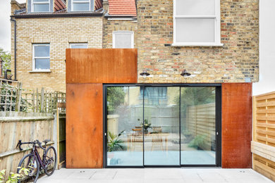 Photo of a medium sized contemporary terraced house in London with three floors, metal cladding, a flat roof and a green roof.