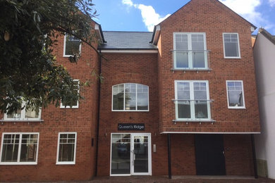 This is an example of a red industrial brick flat in Surrey with three floors, a pitched roof and a tiled roof.
