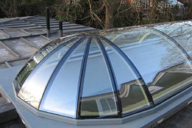 Ejemplo de fachada de casa gris contemporánea con revestimiento de vidrio, tejado plano y tejado de metal