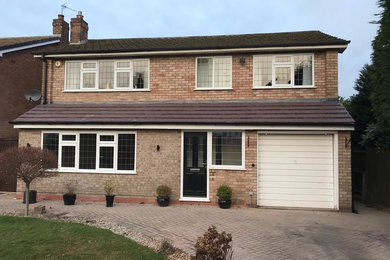 This is an example of a medium sized and beige contemporary bungalow brick detached house in West Midlands with a lean-to roof and a tiled roof.
