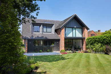Large and red contemporary two floor brick detached house in West Midlands with a hip roof.